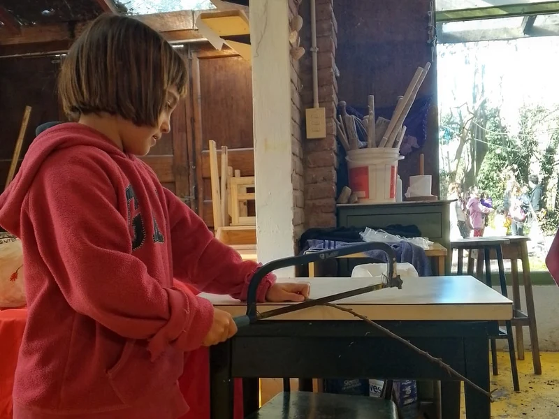 Niña serruchando madera en el taller de KIFF